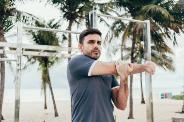 Yakışıklı genç adam sahilde sokak egzersiz yapıyor