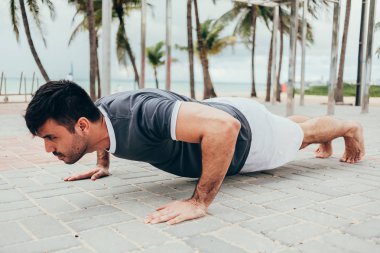 Yakışıklı genç adam sahilde sokak egzersiz yapıyor
