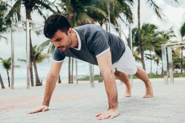 Yakışıklı genç adam sahilde sokak egzersiz yapıyor