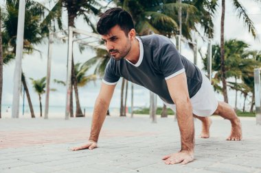 Yakışıklı genç adam sahilde sokak egzersiz yapıyor