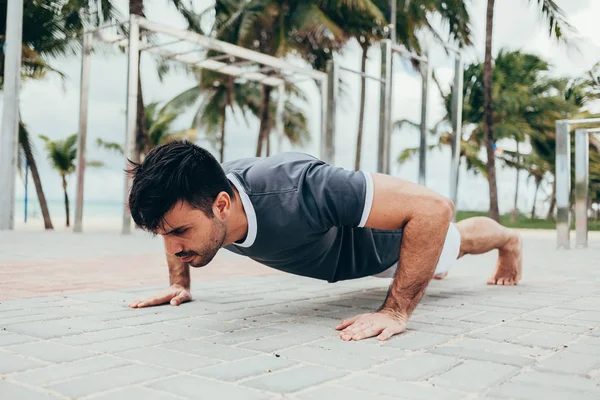 Handsome young man doing street workout on the beach