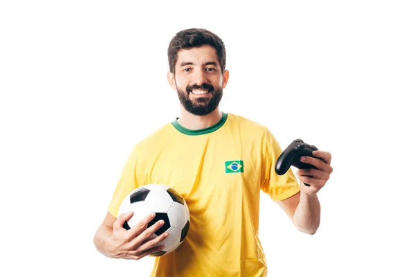 Brazylijski fan piłki nożnej, piłka nożna na sobie mundur żółty i trzymając piłkę i joystick na białym tle — Zdjęcie stockowe