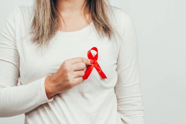 Woman holding red ribbon for HIV illness awareness, 1 December World AIDS Day concept. clipart