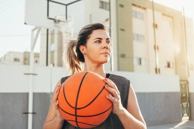Genç bayan basketbolcu yerel bir sahada antrenman yapıyor.