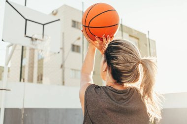 Genç bayan basketbolcu yerel bir sahada antrenman yapıyor.