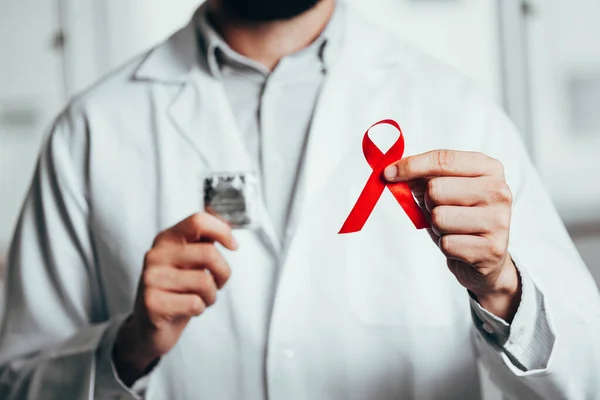 Red ribbon for HIV disease awareness in doctor 's hand, 1 December World AIDS Day concept . — стоковое фото