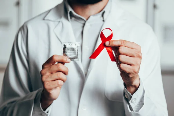 Fita vermelha para conscientização sobre a doença do HIV na mão do médico, 1 de dezembro Conceito do Dia Mundial da AIDS . — Fotografia de Stock