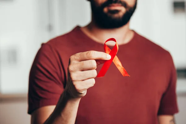 Человек держит красную ленточку для информирования о ВИЧ-инфекции, концепция Всемирного дня борьбы со СПИДом 1 декабря . — стоковое фото