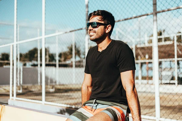 Porträt eines lächelnden Mannes mit Sonnenbrille und T-Shirt, der einen sonnigen Sommertag in der Stadt genießt — Stockfoto