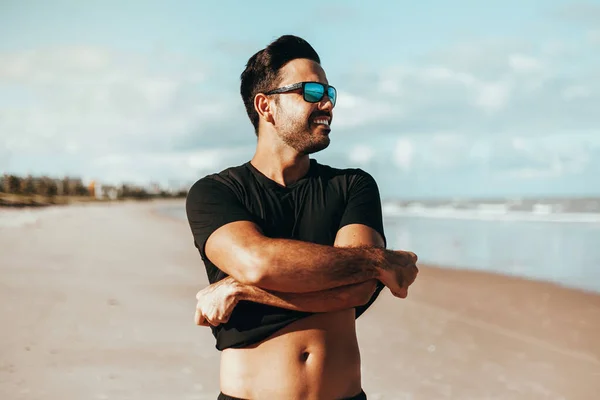 Sommerzeit. Lächelnder Mann zieht sein Hemd am Strand aus — Stockfoto