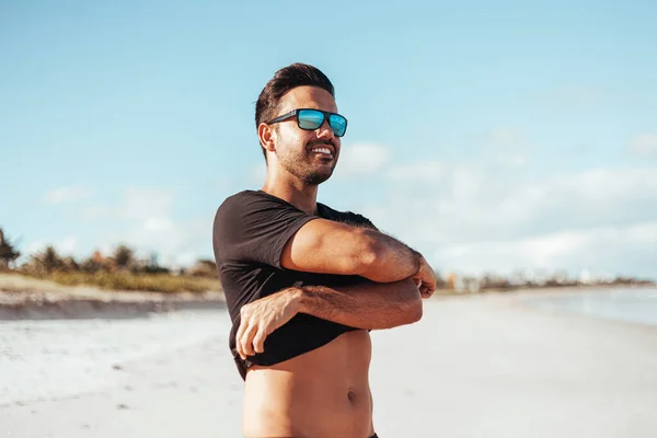 Sommerzeit. Lächelnder Mann zieht sein Hemd am Strand aus — Stockfoto