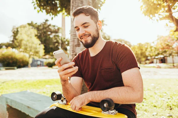 Молодой фигурист пользуется смартфоном в парке — стоковое фото