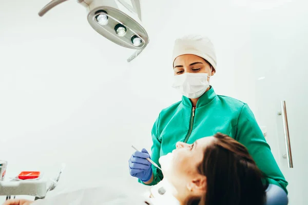 Žena zubař vyšetření pacienta na její klinice — Stock fotografie