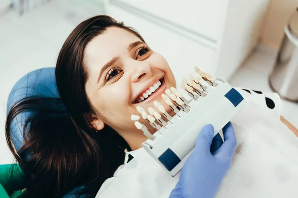 Dentista comparando el tono de los dientes del paciente con muestras de bleachi — Foto de Stock