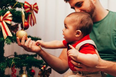 Oyuncu baba küçük oğluna Noel ağacını gösteriyor.