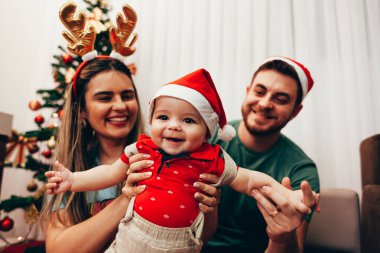 Genç bir aile Noel 'i evde kutluyor. Genç ve mutlu bir aile birlikte tatilin tadını çıkarıyor..