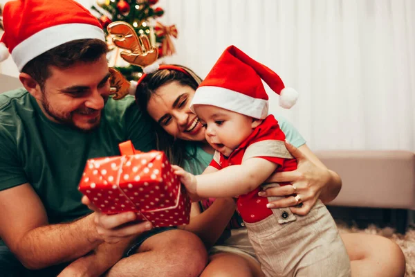 Keluarga muda merayakan Natal di rumah. Keluarga muda yang bahagia menikmati liburan mereka bersama . — Stok Foto
