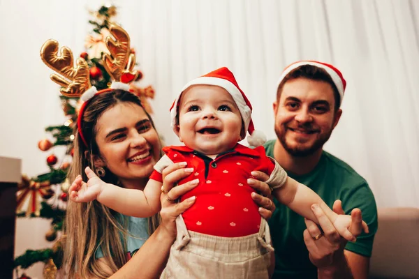 Keluarga muda merayakan Natal di rumah. Keluarga muda yang bahagia menikmati liburan mereka bersama . — Stok Foto