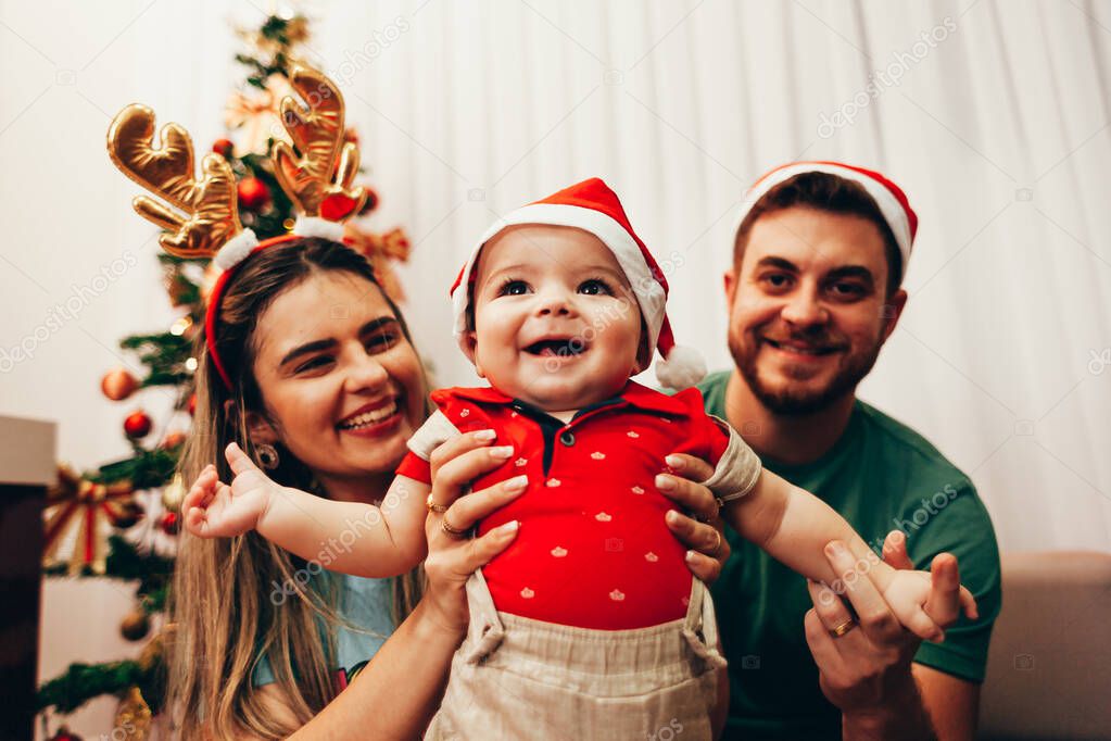 Young family celebrating Christmas at home. Happy young family enjoying their holiday time together.