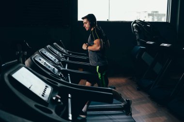Spor salonunda koşu bandında koşan yalnız bir adam.