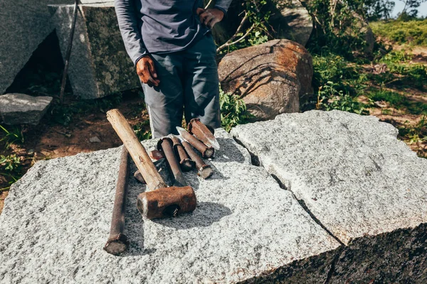 Extracción de granito para pavimentar adoquines. Trabajador y sus herramientas . — Foto de Stock