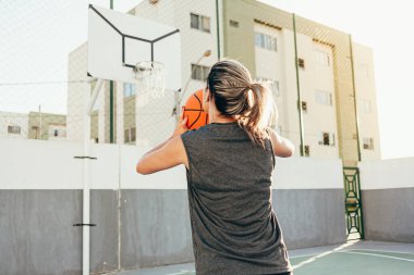 Genç bayan basketbolcu yerel bir sahada antrenman yapıyor.
