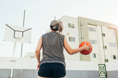 Genç bayan basketbolcu yerel bir sahada antrenman yapıyor.