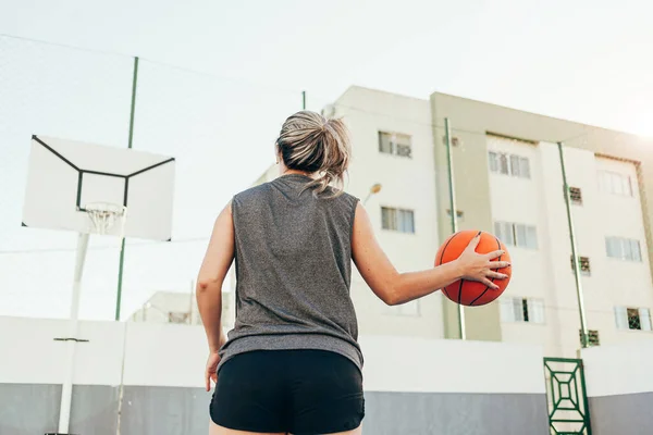 Young female basketball player training outdoors on a local court