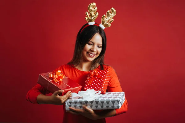 Portrait of woman wearing reindeer antlers hat holding gift boxes