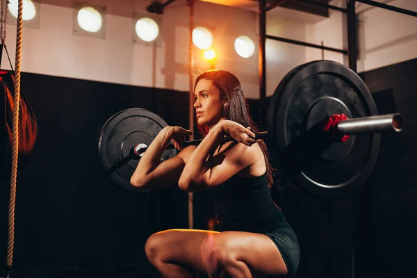 Een gespierde vrouw in de sportschool die zware gewichtoefeningen doet. Jonge vrouw — Stockfoto