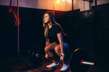 Spor salonundaki kaslı kadın ağır ağırlık egzersizleri yapıyor. Sağlık kulübünde ağırlık kaldıran genç bir kadın.