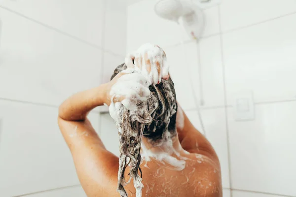 Rückseite der schönen nackten jungen Frau unter der Dusche im Badezimmer — Stockfoto