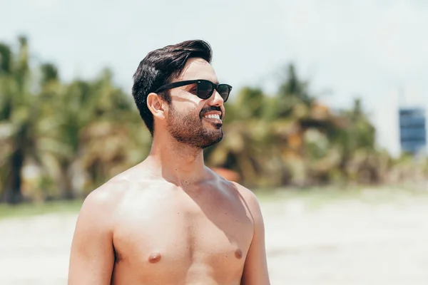 Усміхнений чоловік у сонцезахисних окулярах на тропічному пляжі — стокове фото