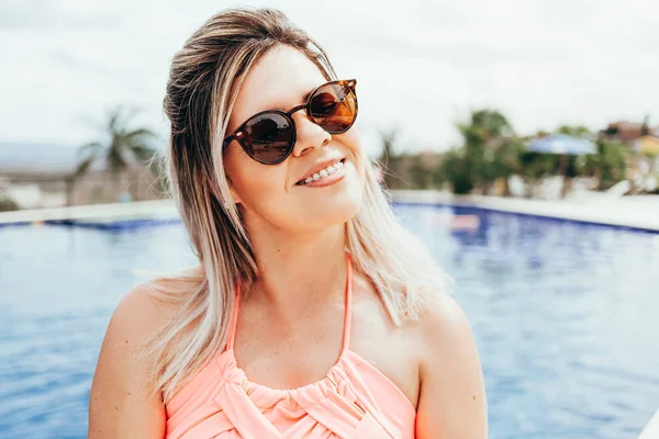 Portrait of young smiling woman with blue pool in the background — 스톡 사진