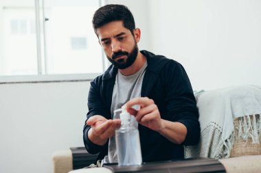 Coronavirus, covid-19 ve karantina konsepti. Karantinadaki adam ellerini alkol jeliyle temizliyor.