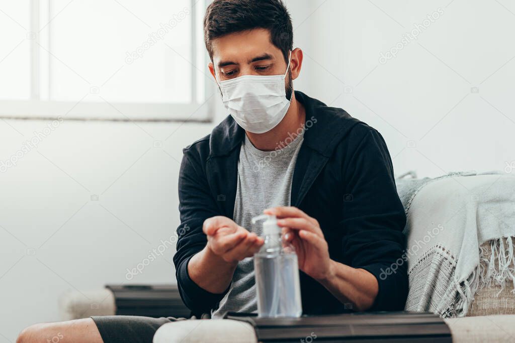 Coronavirus. Man in quarantine wearing protective mask sanitizing his hands with alcohol gel