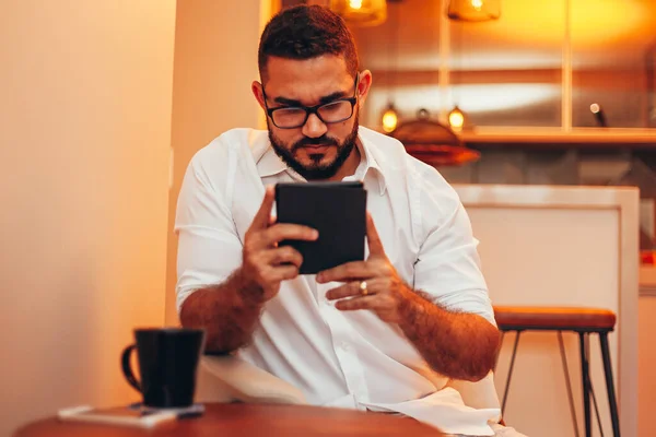 Man relaxes reading book on e-book reader at his home