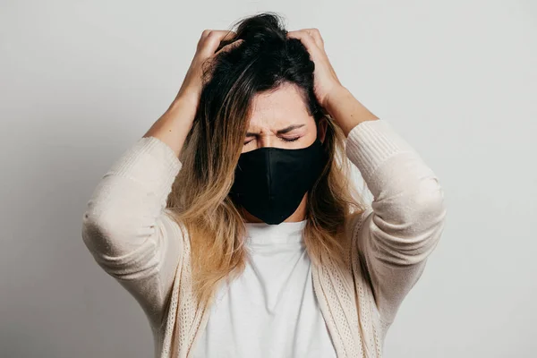 Stressed woman wearing face protection mask. Mental health concept during the Covid-19 pandemic.