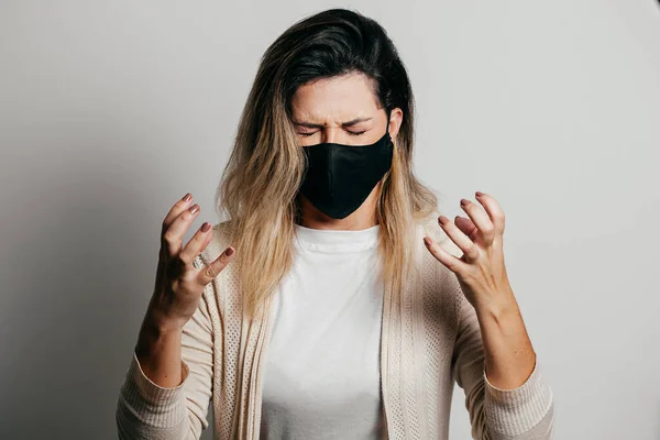 Stressed woman wearing face protection mask. Mental health concept during the Covid-19 pandemic.