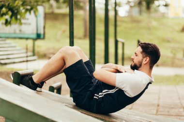 Spor giyimli bir adam halka açık bir parkta mekik çekiyor..