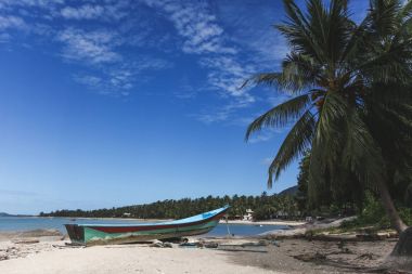 güneşli günde eski tekne ile sakin tropikal plaj