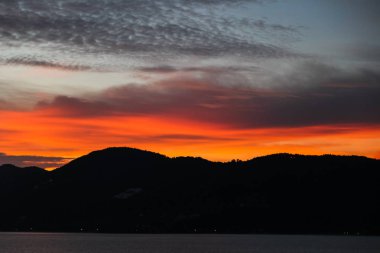 black hills silhouette under orange sunset sky clipart