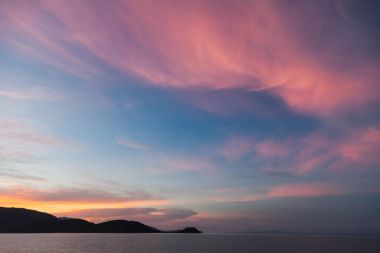 güzel gün batımı deniz manzarası pembe bulutlu gökyüzü altında