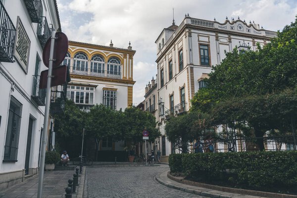 view of city street with trees and buildings under cloudy sky, spain