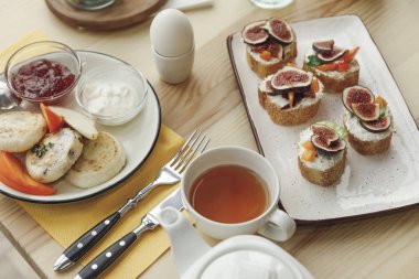 close-up view of tasty healthy breakfast with cheesecakes fritters and canapes with figs on table  clipart