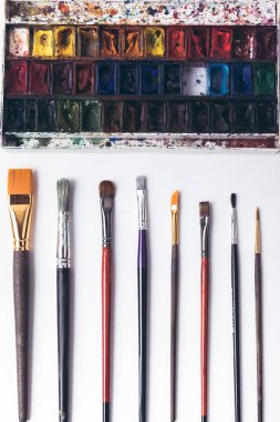 top view of well ordered paintbrushes and watercolour paints at designer workplace   clipart