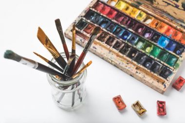 close-up view of watercolor paints and paintbrushes in glass on white clipart