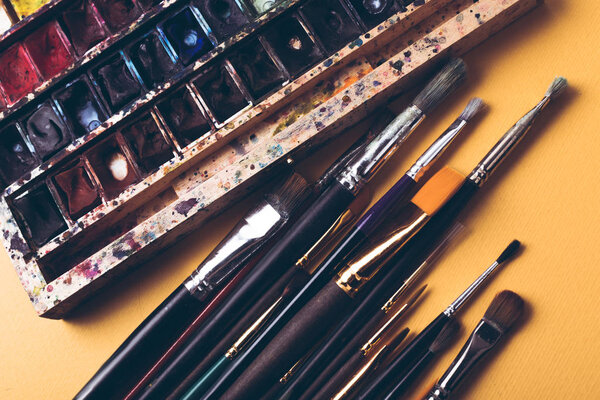 top view of paint brushes and watercolour paints at designer workplace 