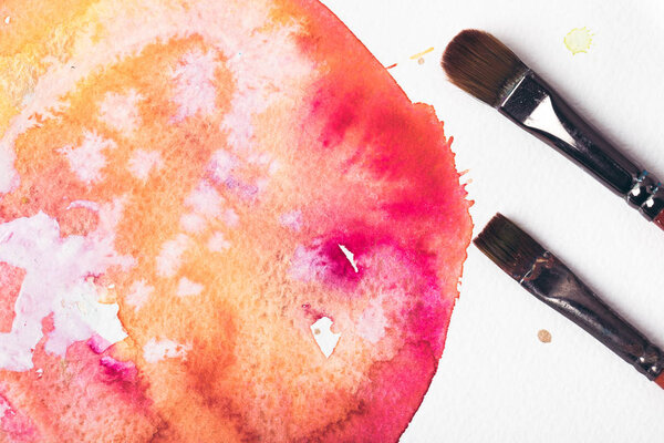 Крупный план кистей и абстрактный акварельный рисунок на белом
