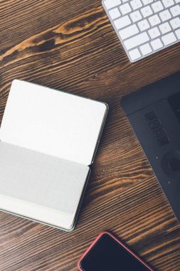ahşap masa üzerinde boş açık defter, smartphone, grafik tablet ve bilgisayar klavye Üstten Görünüm